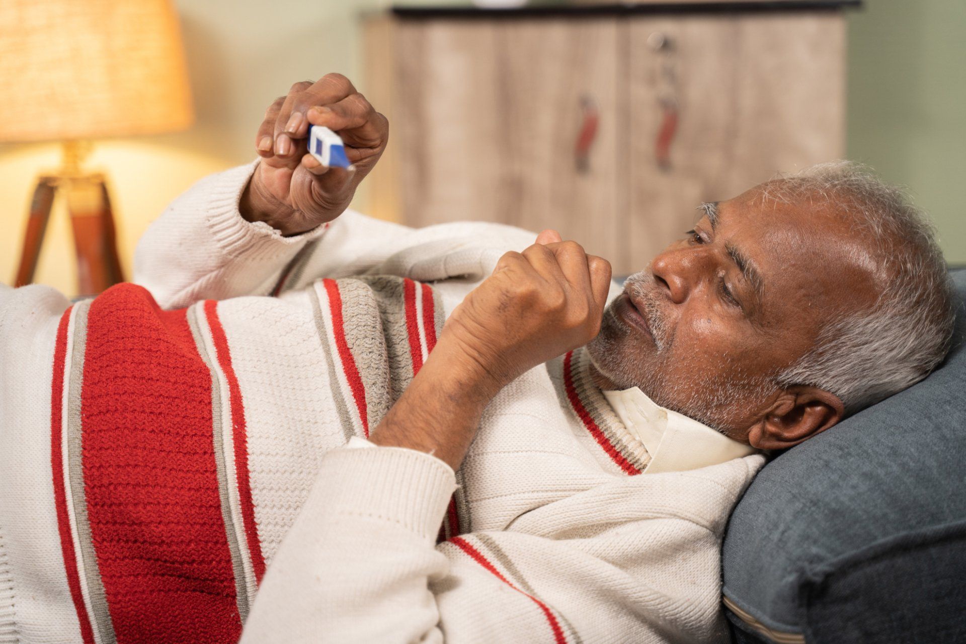 Senior man coughing and checking his temperature