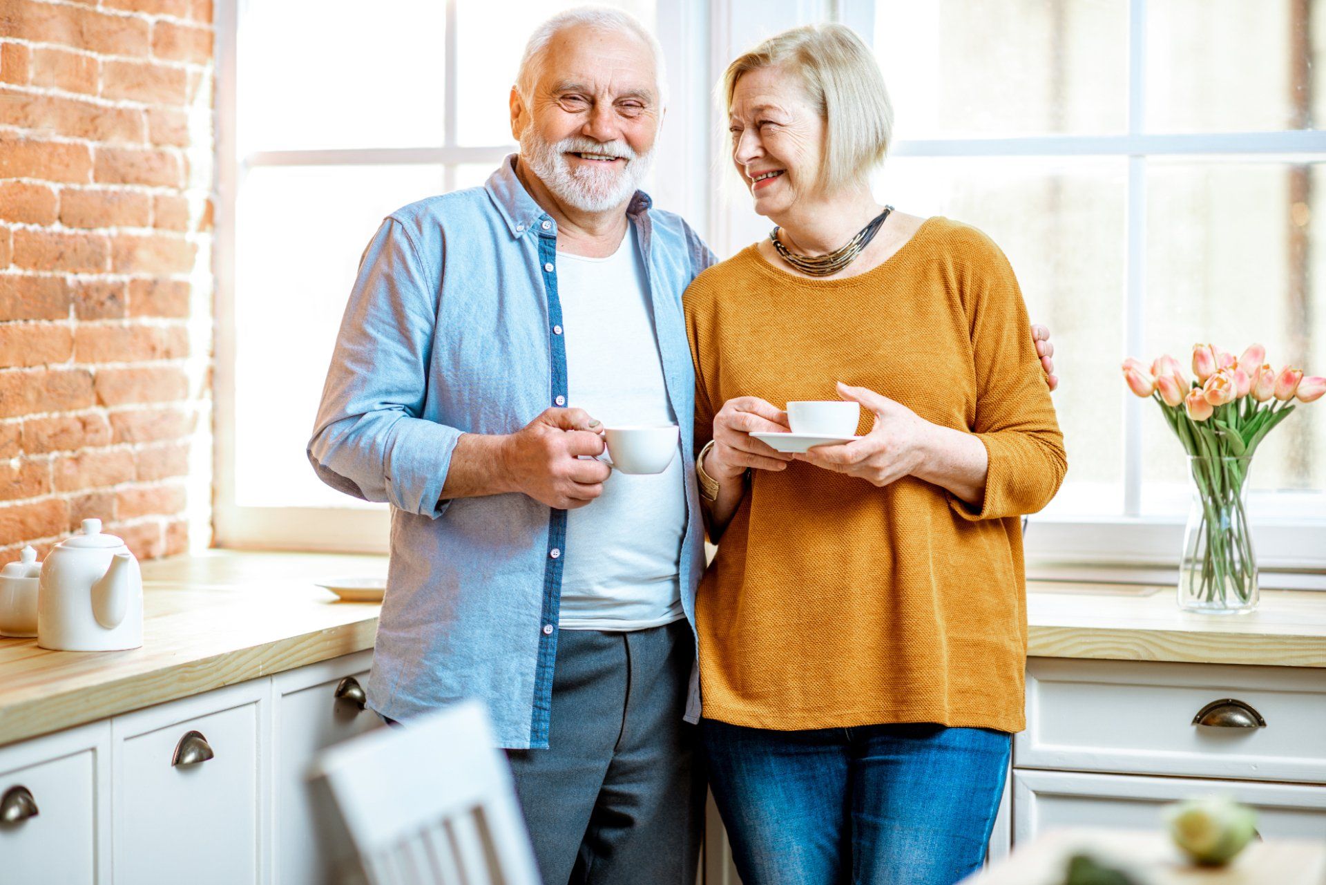 Older couple holding coffee cups in their kitchen