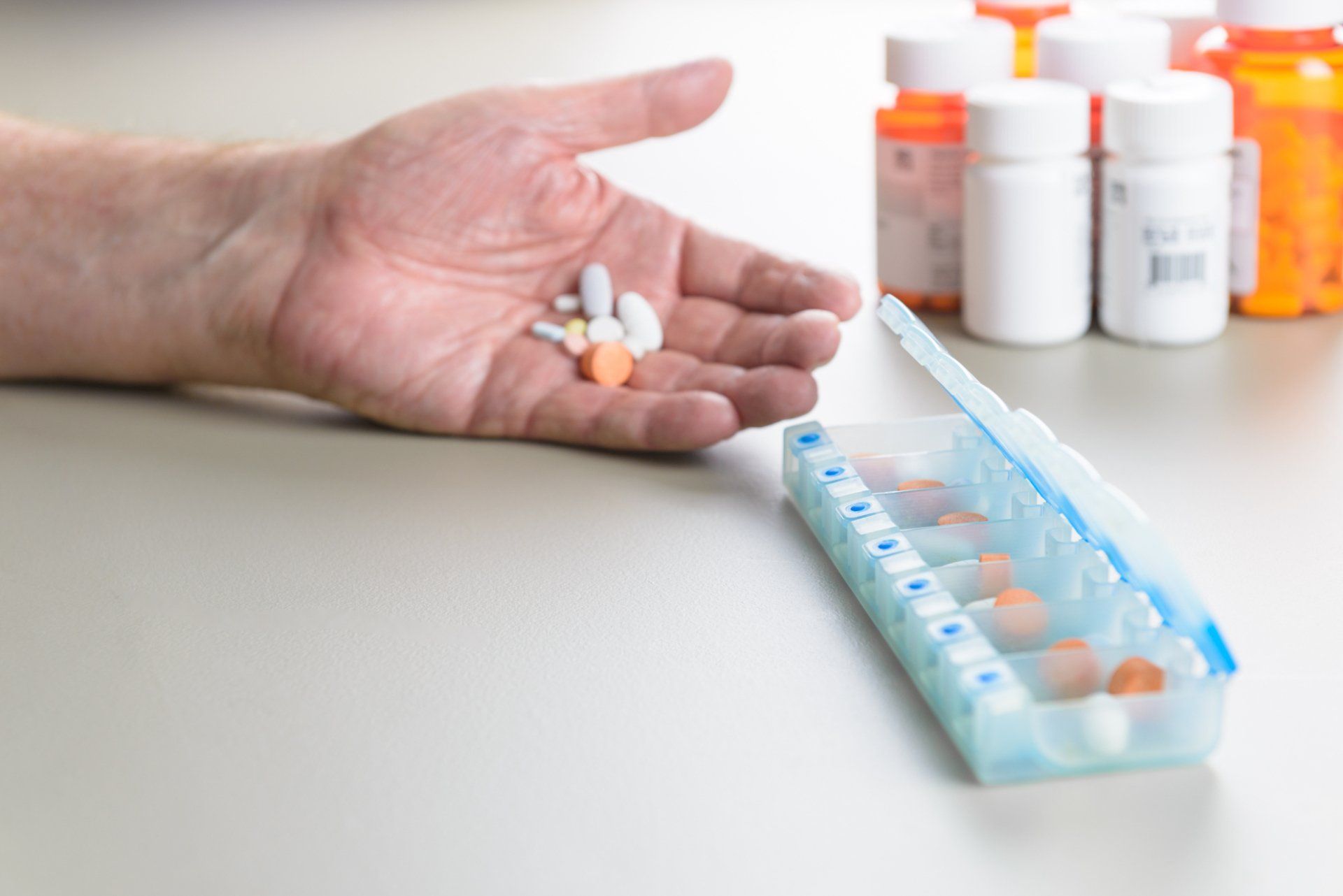 Older adult sorting medication into a divided box