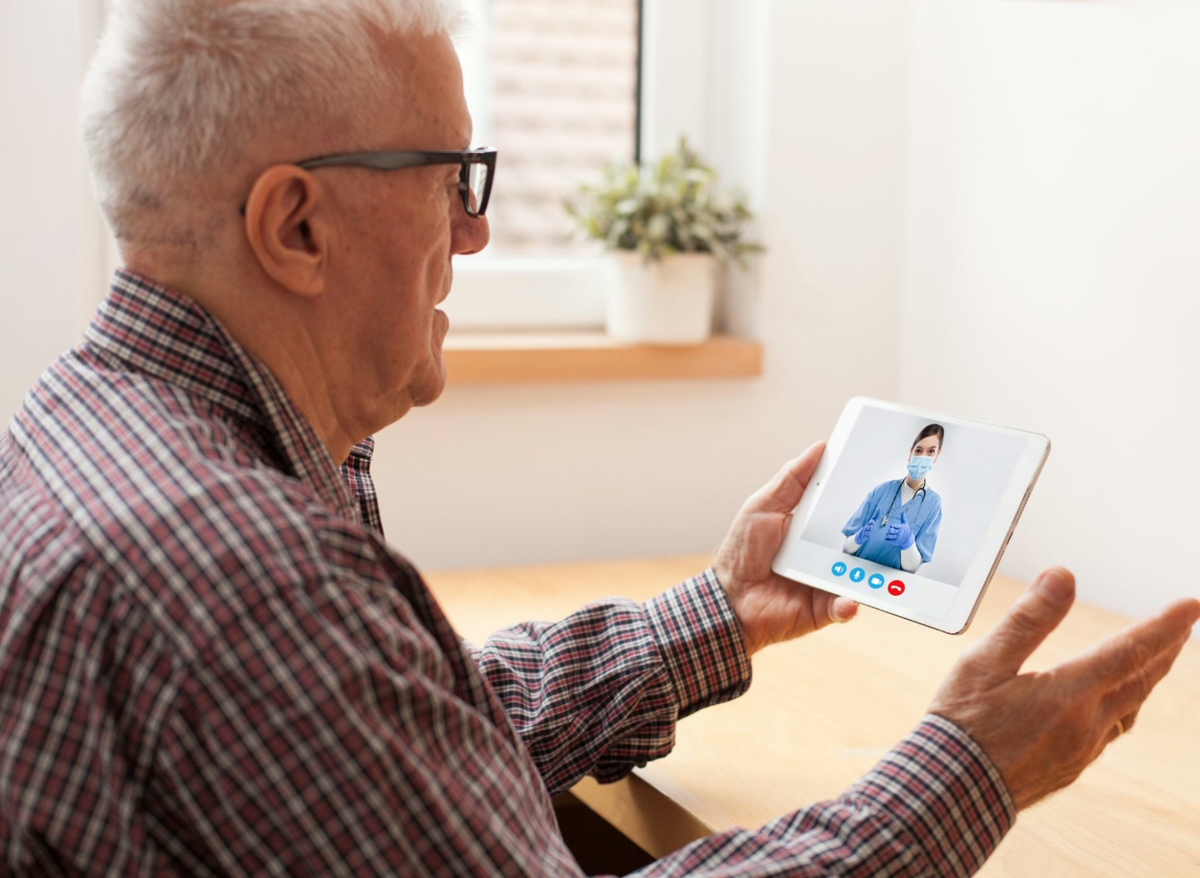 Older man speaking with a doctor by telehealth video call